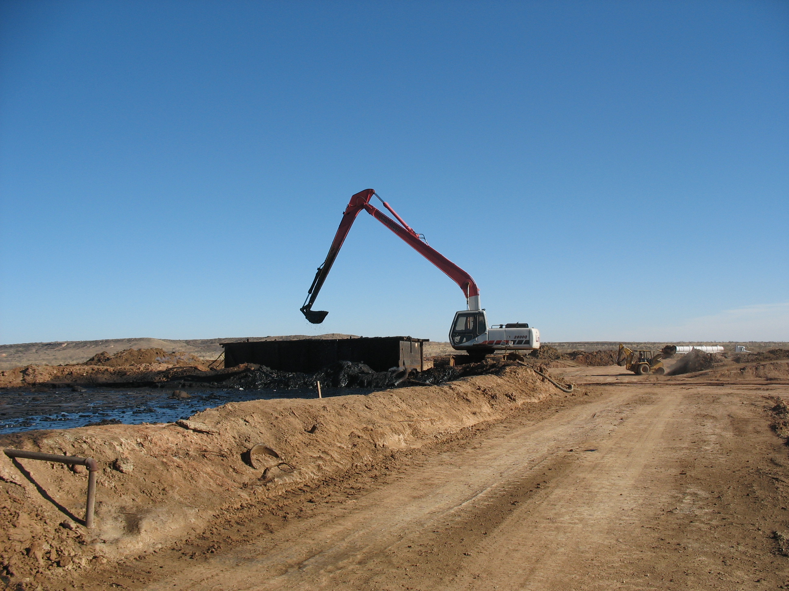 Excavator working at an oil-sludge lake at the Parabo Disposal Facility